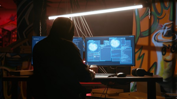Hacker in dark neon lit underground HQ coding malware